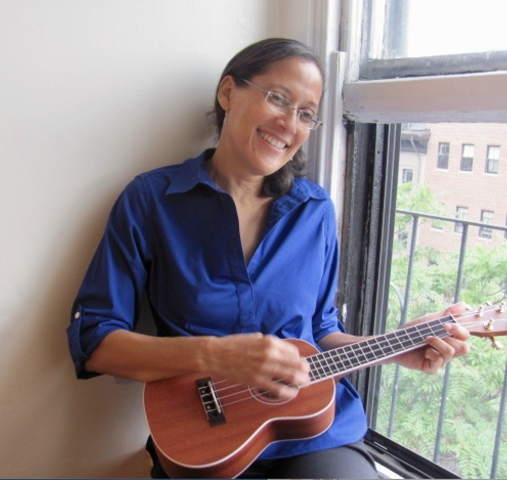 Dr. Yvette Colón sitting on a windowsill playing the ukulele. 